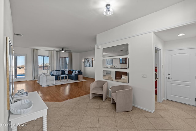 living room with light tile patterned floors, a ceiling fan, visible vents, and baseboards