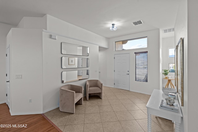 foyer entrance featuring light tile patterned floors, visible vents, and baseboards