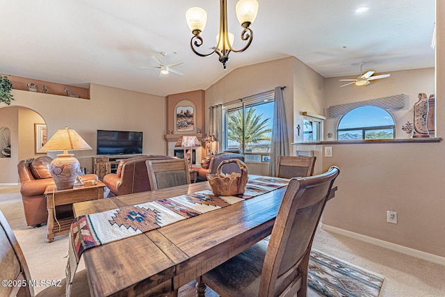 carpeted dining area featuring ceiling fan with notable chandelier, baseboards, and a healthy amount of sunlight