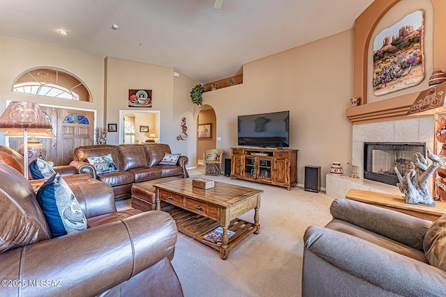 living area with a fireplace, carpet, arched walkways, and high vaulted ceiling