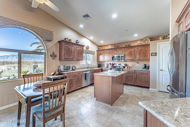 kitchen featuring visible vents, a kitchen island, a sink, vaulted ceiling, and appliances with stainless steel finishes