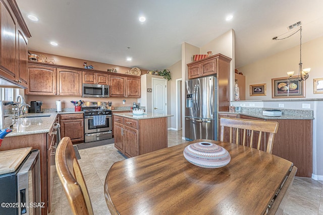 kitchen featuring visible vents, lofted ceiling, a sink, appliances with stainless steel finishes, and a center island