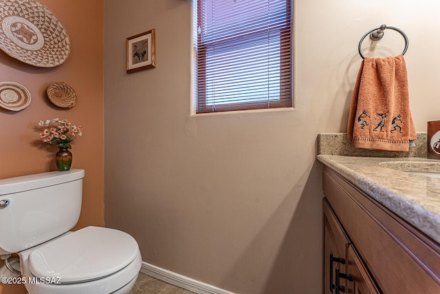 half bathroom featuring toilet, vanity, and baseboards