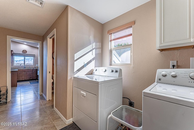 clothes washing area with visible vents, cabinet space, independent washer and dryer, and a sink