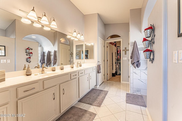 full bath with a walk in closet, double vanity, tile patterned floors, and a sink