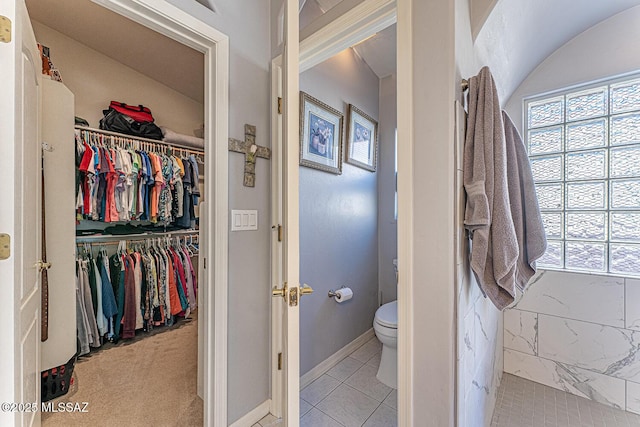 bathroom featuring a spacious closet, tile patterned flooring, toilet, and baseboards