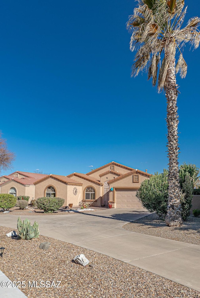 mediterranean / spanish house featuring a tile roof, an attached garage, driveway, and stucco siding