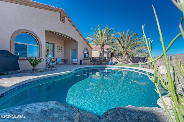 view of pool with a patio, fence, a fenced in pool, and grilling area