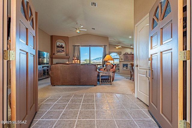 carpeted entrance foyer with a fireplace, lofted ceiling, a ceiling fan, and visible vents