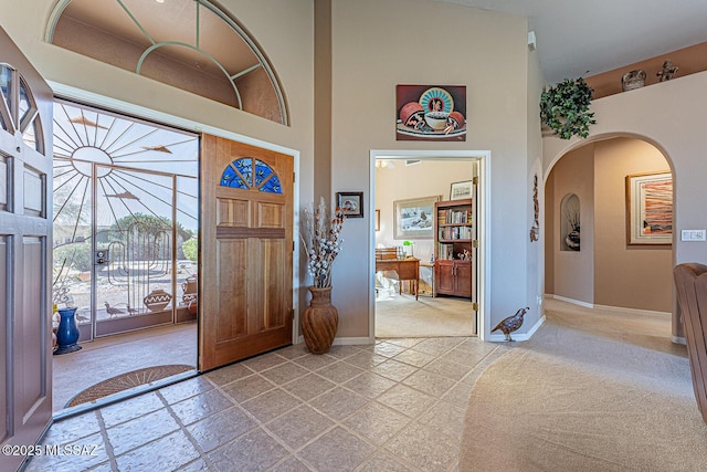 entrance foyer featuring a high ceiling, baseboards, and arched walkways