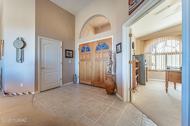 entryway with baseboards, high vaulted ceiling, and carpet flooring