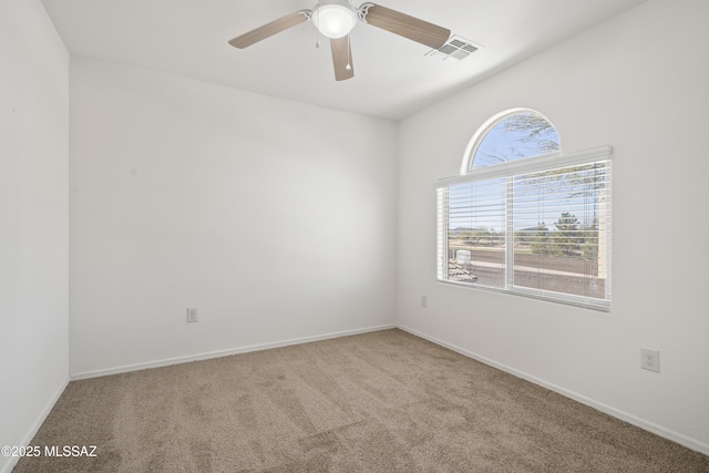 carpeted spare room with baseboards, ceiling fan, and visible vents