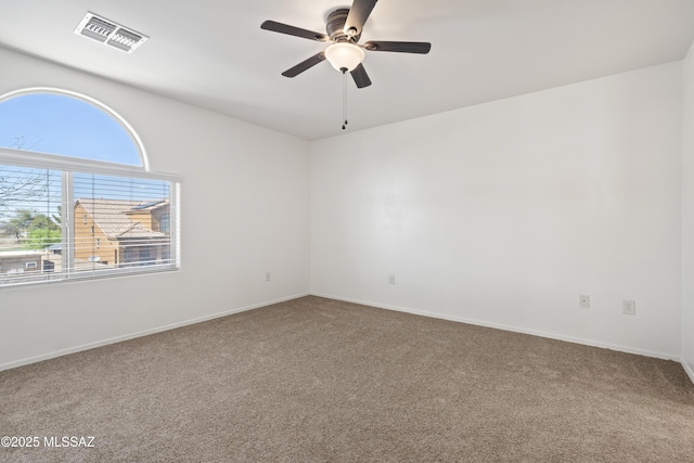 carpeted spare room with baseboards, visible vents, and a ceiling fan