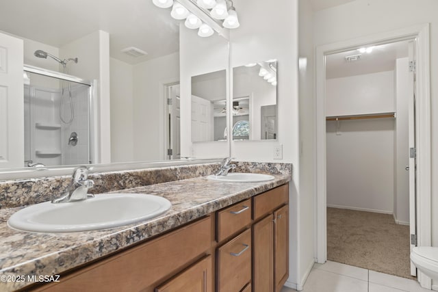 bathroom featuring a shower with door, visible vents, a sink, and double vanity