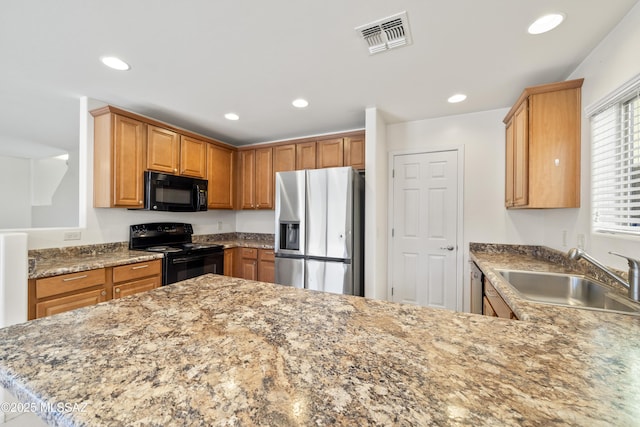 kitchen with light stone counters, a sink, visible vents, black appliances, and recessed lighting