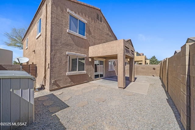 back of property with stucco siding, a fenced backyard, and a patio
