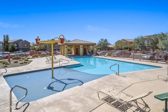 community pool with a patio and fence