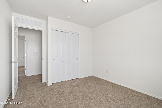 unfurnished bedroom with a closet, carpet floors, and baseboards