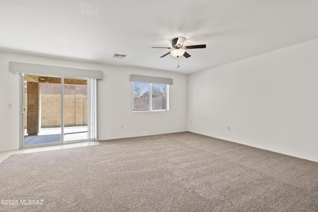 carpeted empty room featuring baseboards, visible vents, and a ceiling fan