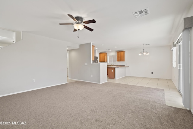 unfurnished living room with light tile patterned flooring, ceiling fan with notable chandelier, light colored carpet, visible vents, and recessed lighting
