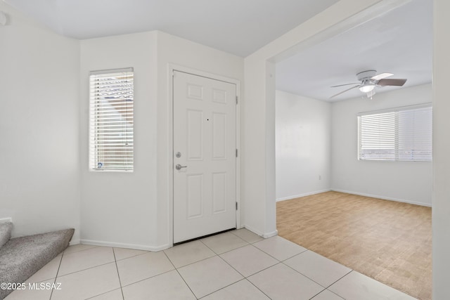 foyer with a wealth of natural light, a ceiling fan, and light tile patterned floors
