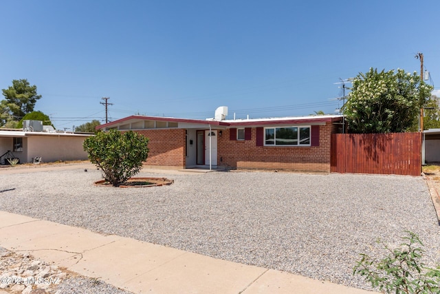 ranch-style home featuring brick siding and fence