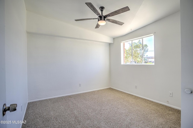 carpeted spare room with vaulted ceiling, baseboards, and a ceiling fan