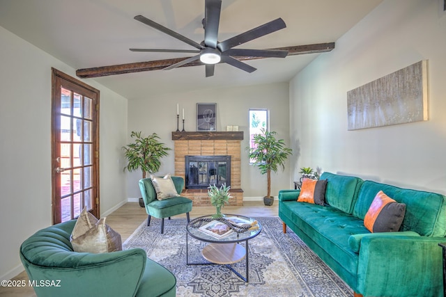 living room featuring a fireplace, ceiling fan, baseboards, and beam ceiling