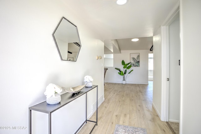 corridor featuring baseboards, light wood finished floors, and recessed lighting