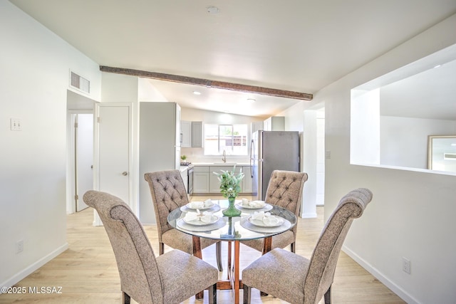 dining room with light wood finished floors, lofted ceiling with beams, baseboards, and visible vents