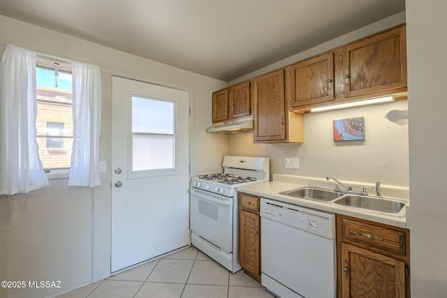 kitchen featuring under cabinet range hood, light countertops, brown cabinetry, white appliances, and a sink