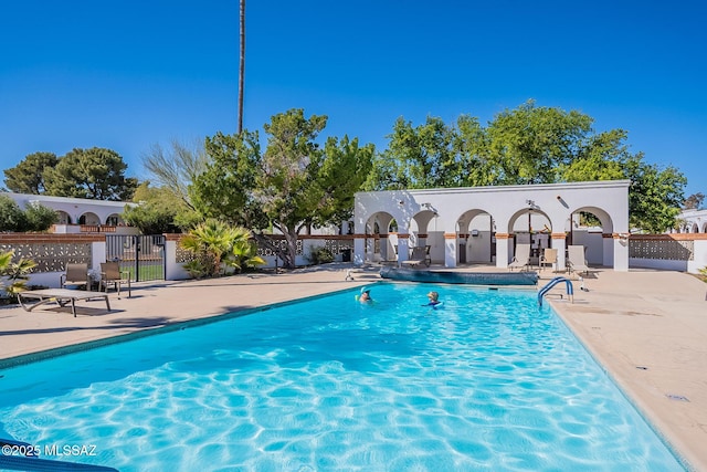 pool with a patio area and fence