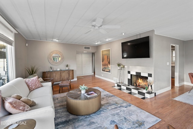 living area with visible vents, baseboards, wood finished floors, and a tile fireplace