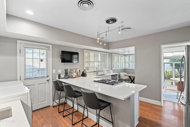 kitchen with visible vents, light wood finished floors, separate washer and dryer, a sink, and stainless steel appliances