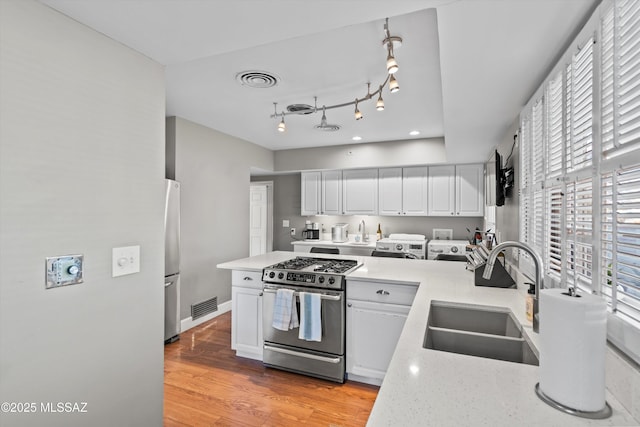 kitchen featuring visible vents, light wood-style flooring, a sink, stainless steel appliances, and white cabinets