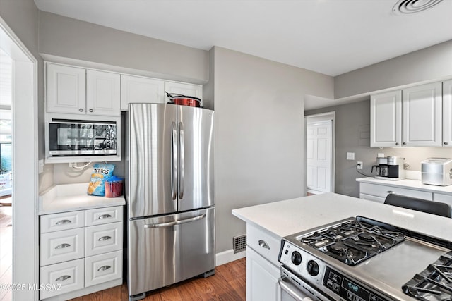 kitchen featuring wood finished floors, visible vents, stainless steel appliances, light countertops, and white cabinets