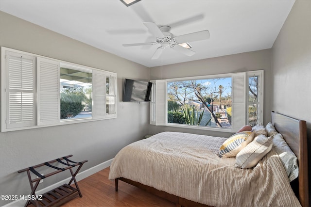 bedroom with multiple windows, ceiling fan, baseboards, and wood finished floors