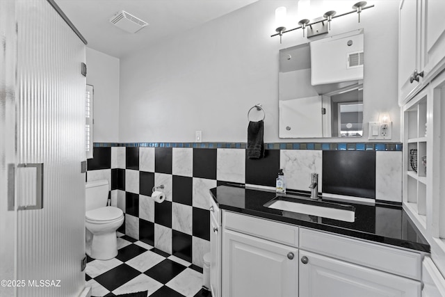 bathroom featuring vanity, tile walls, toilet, and visible vents