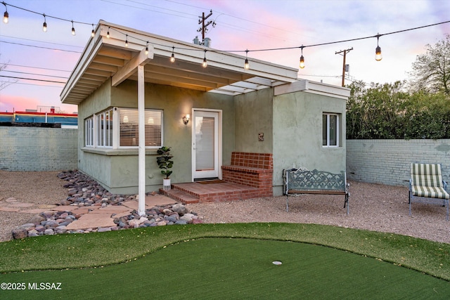 exterior space with fence, brick siding, and stucco siding