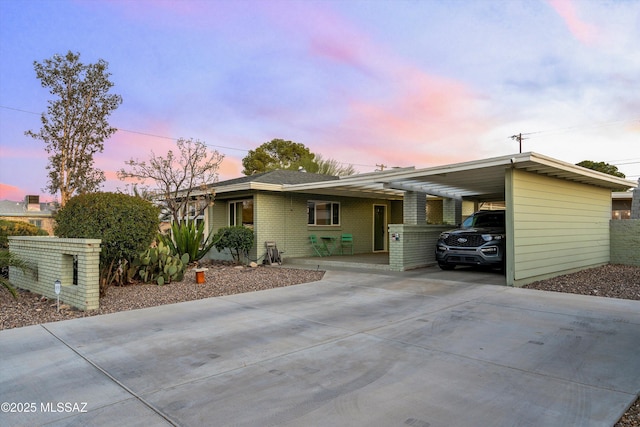 view of front of home featuring brick siding, a carport, and driveway