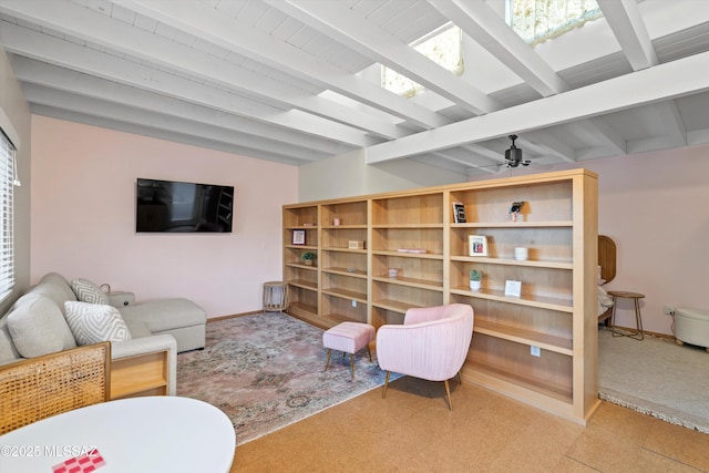 living area featuring beam ceiling, baseboards, and a ceiling fan