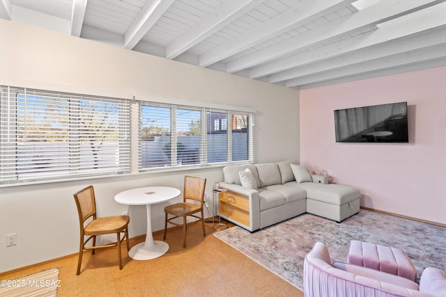 living area with baseboards and beam ceiling