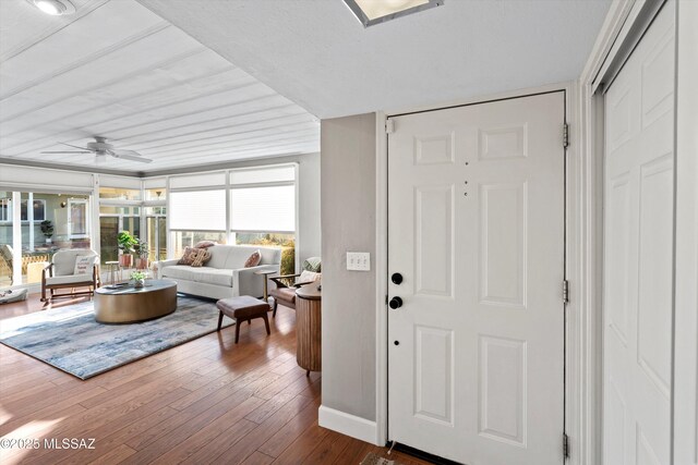 foyer entrance with dark wood finished floors, baseboards, and ceiling fan