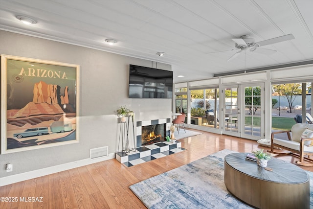 living area featuring visible vents, baseboards, a tiled fireplace, french doors, and wood finished floors