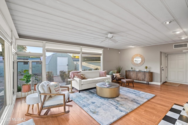 living area with visible vents, ceiling fan, baseboards, and wood finished floors