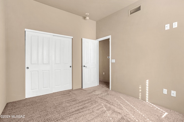 unfurnished bedroom with carpet flooring, visible vents, and a closet