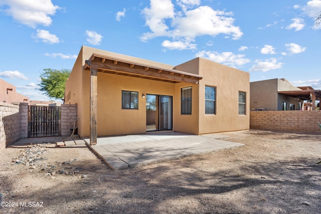 back of house with a gate, stucco siding, a patio, and fence