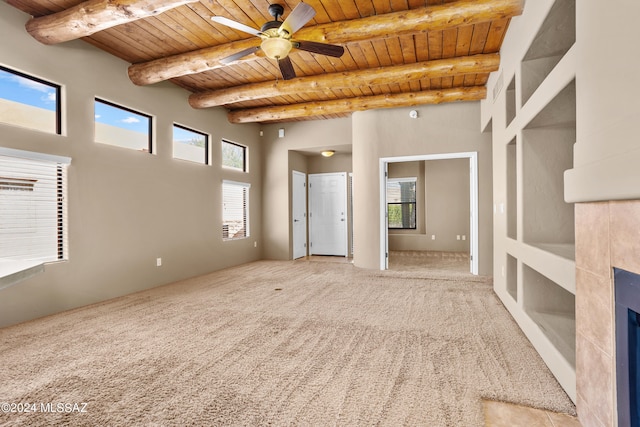 interior space featuring beam ceiling, a ceiling fan, a tiled fireplace, wood ceiling, and a towering ceiling