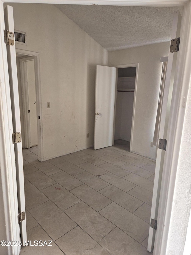 unfurnished bedroom with light tile patterned floors, visible vents, a textured ceiling, and a closet