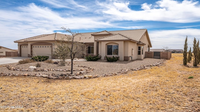 view of front of property with fence, concrete driveway, a tile roof, stucco siding, and a garage